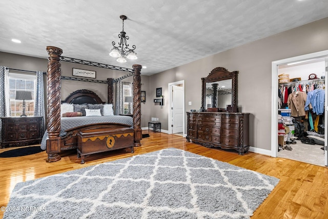 bedroom featuring a chandelier, a spacious closet, a closet, and light hardwood / wood-style flooring