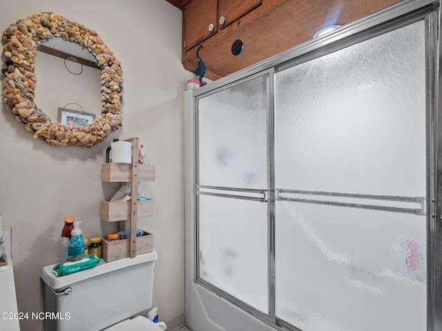 bathroom with toilet and bath / shower combo with glass door