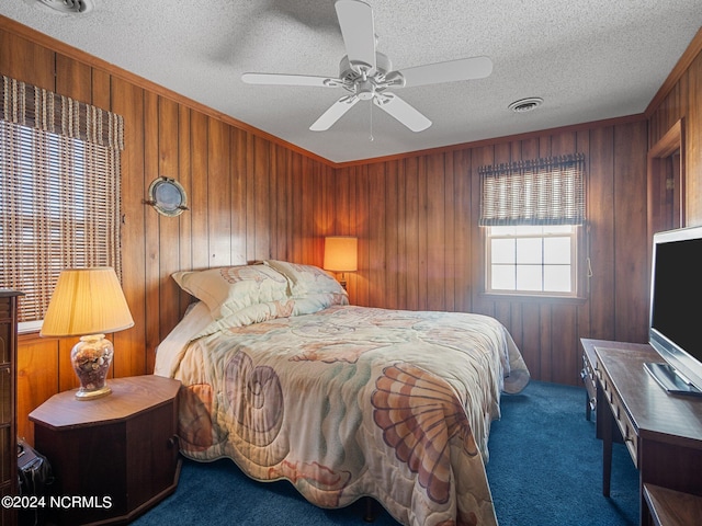 carpeted bedroom featuring a textured ceiling, ceiling fan, and wooden walls