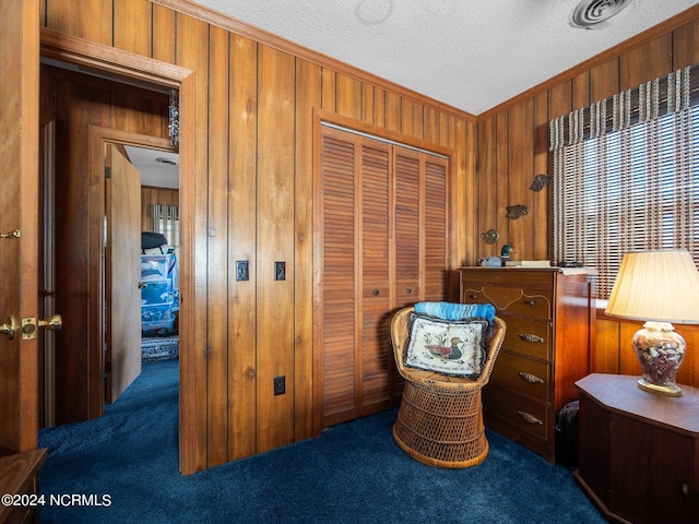 living area with carpet flooring, a textured ceiling, and wood walls