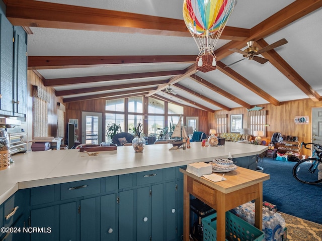 kitchen featuring carpet, vaulted ceiling with beams, wood walls, and blue cabinetry