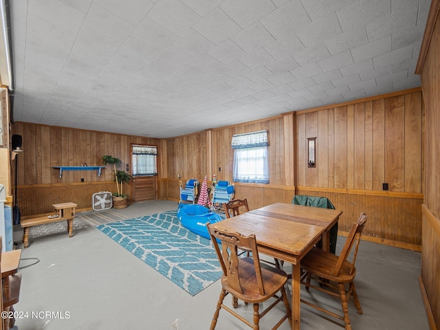 dining room with wooden walls and concrete floors