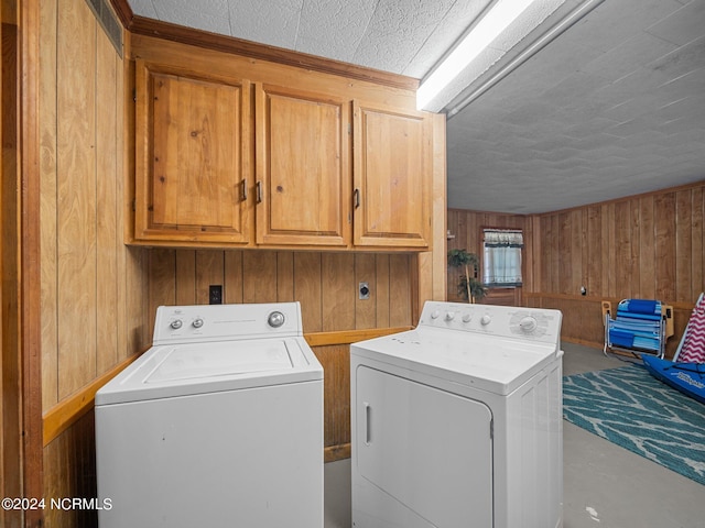 laundry area featuring washer and dryer, cabinets, and wooden walls