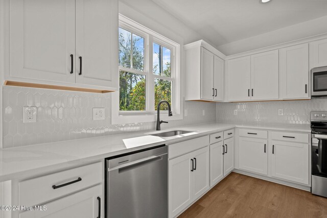 4865 Scarlet Sage Way, Shallotte, NC 28470 - kitchen with stainless steel appliances, white cabinets, light wood finished floors, and tasteful backsplash