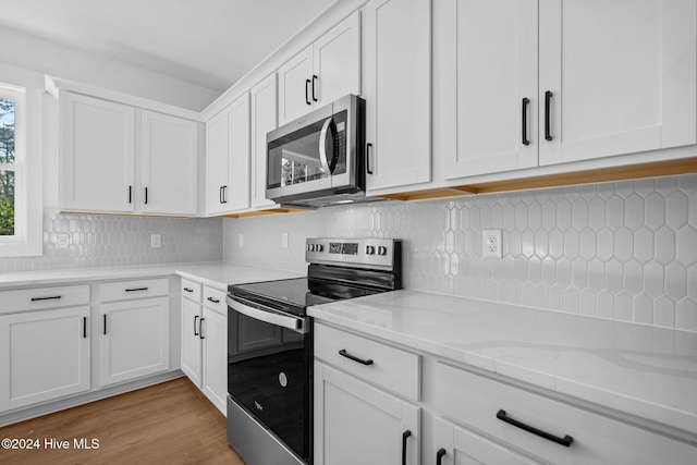 4865 Scarlet Sage Way, Shallotte, NC 28470 - kitchen featuring stainless steel appliances, white cabinetry, light wood finished floors, tasteful backsplash, and light stone countertops