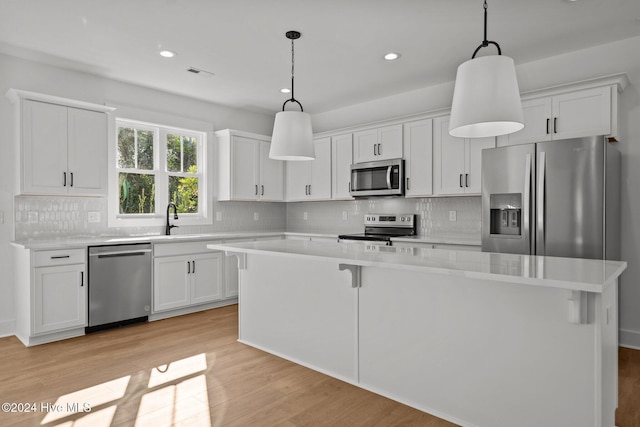 4865 Scarlet Sage Way, Shallotte, NC 28470 - kitchen featuring stainless steel appliances, light wood finished floors, a center island, white cabinetry, and recessed lighting
