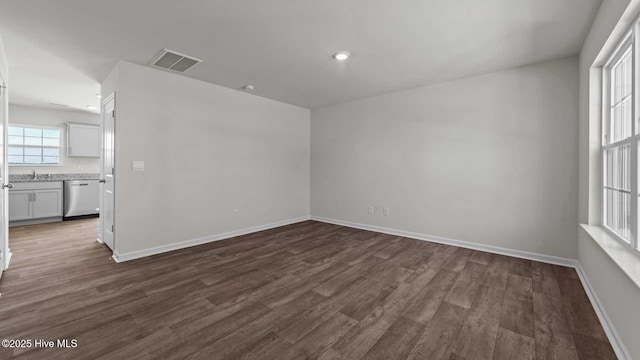 spare room featuring dark wood finished floors, visible vents, and baseboards