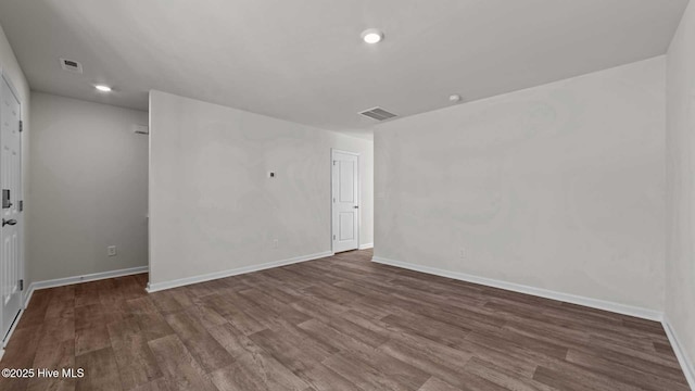 empty room featuring wood finished floors, visible vents, and baseboards