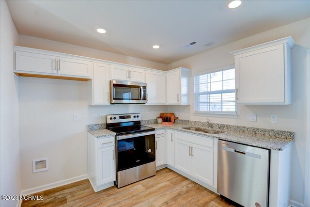 kitchen with visible vents, white cabinetry, stainless steel appliances, and a sink