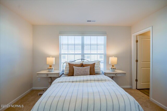 bedroom featuring light carpet, visible vents, and baseboards