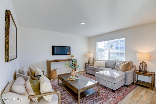 living room with visible vents, light wood-style flooring, and baseboards