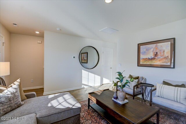 living area with visible vents, baseboards, and wood finished floors