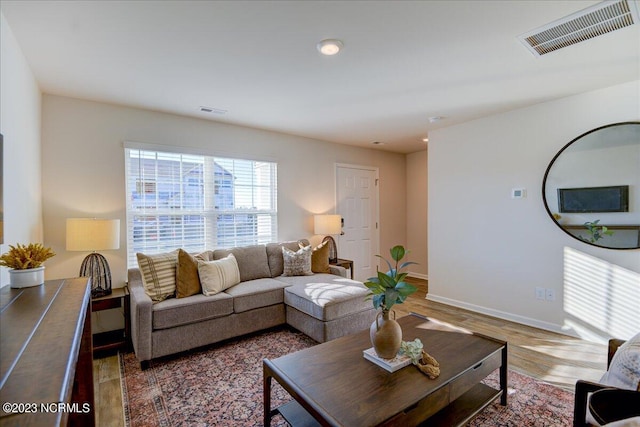 living room with visible vents, baseboards, and wood finished floors