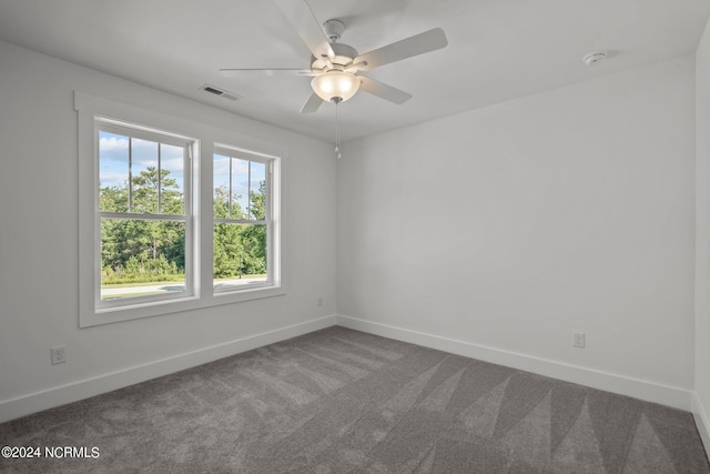 carpeted empty room with baseboards, visible vents, and ceiling fan