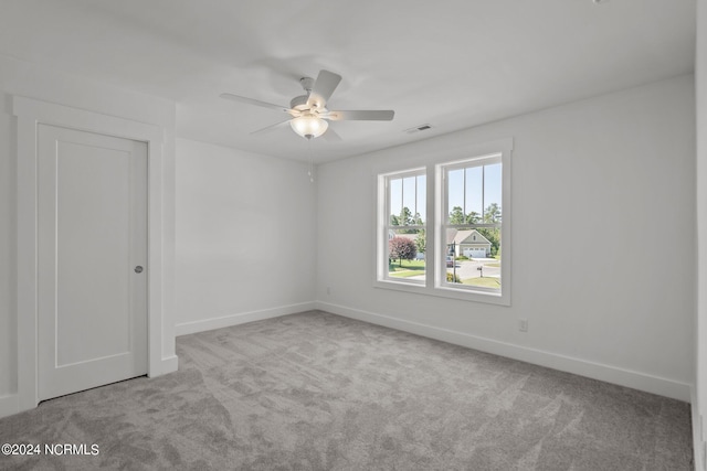 carpeted spare room featuring ceiling fan, visible vents, and baseboards