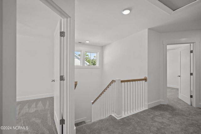 hallway with carpet, baseboards, and an upstairs landing