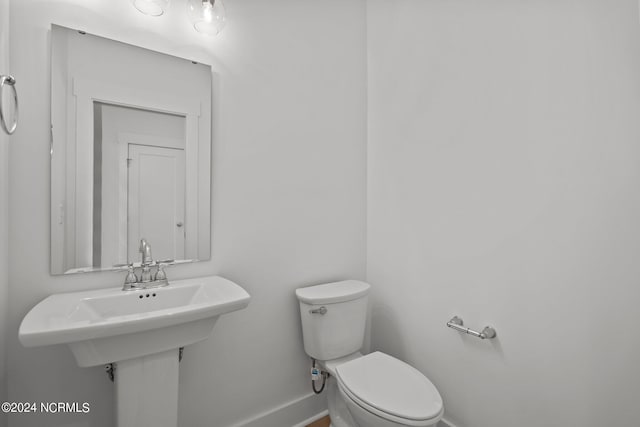 half bath featuring toilet and baseboards