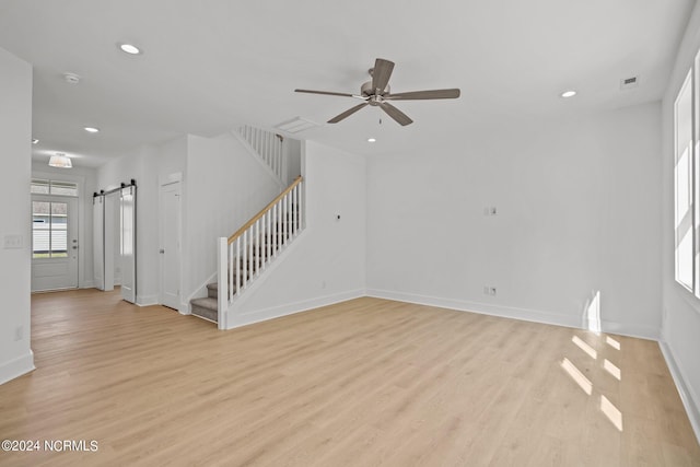 spare room featuring stairs, a barn door, light wood-type flooring, and recessed lighting