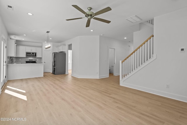 unfurnished living room with light wood finished floors, stairs, visible vents, and a sink