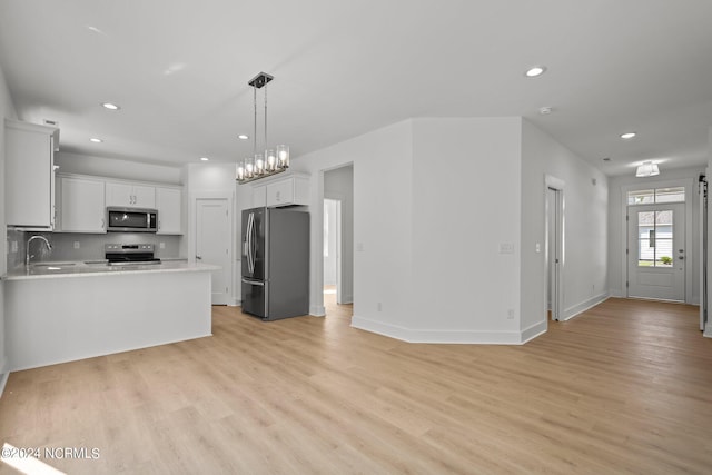 kitchen featuring light wood-style floors, stainless steel appliances, light countertops, and open floor plan