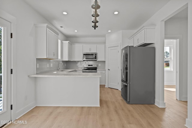 kitchen with light countertops, appliances with stainless steel finishes, a sink, and a wealth of natural light