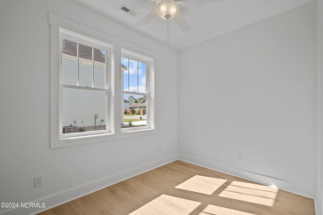 spare room with a ceiling fan, visible vents, baseboards, and wood finished floors