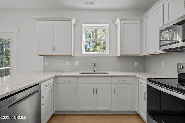 kitchen featuring visible vents, decorative backsplash, stainless steel appliances, white cabinetry, and a sink