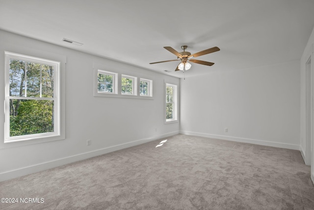 carpeted empty room with visible vents, ceiling fan, and baseboards