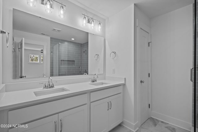 full bath with marble finish floor, double vanity, a stall shower, and a sink