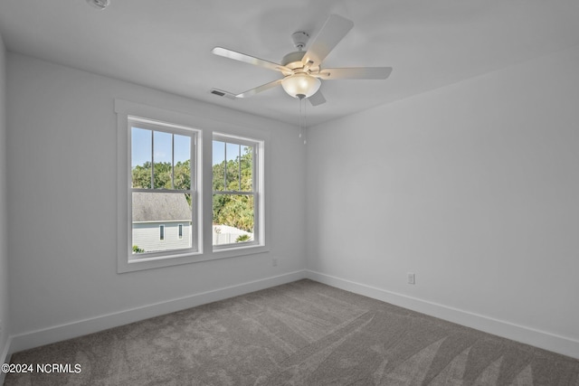 carpeted spare room with baseboards, visible vents, and ceiling fan