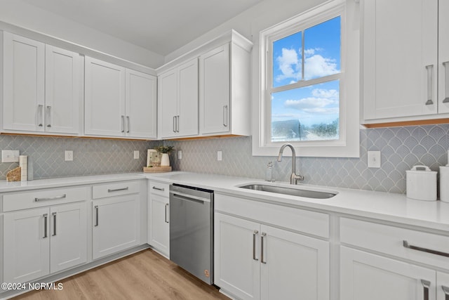 kitchen featuring a sink, white cabinets, light countertops, stainless steel dishwasher, and light wood finished floors