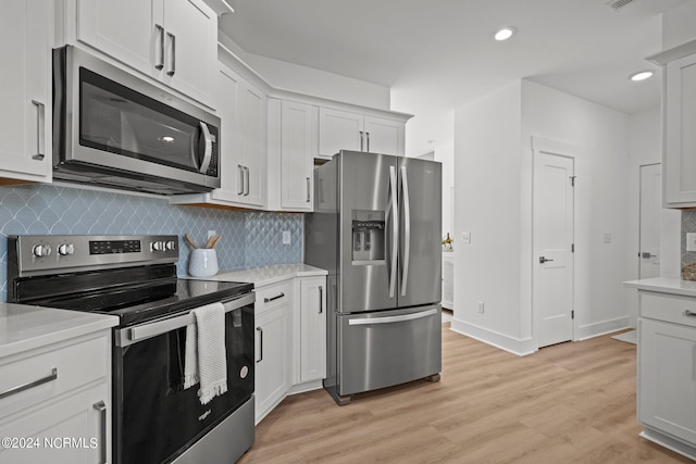 kitchen featuring light wood finished floors, stainless steel appliances, light countertops, backsplash, and recessed lighting