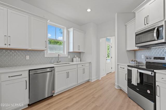 kitchen featuring a sink, white cabinetry, light wood-style floors, light countertops, and appliances with stainless steel finishes