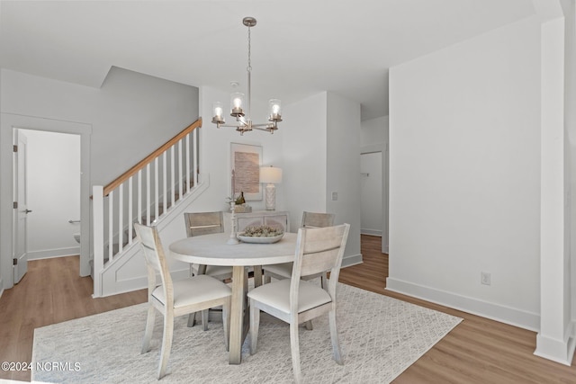 dining area featuring light wood finished floors, baseboards, stairway, and a chandelier