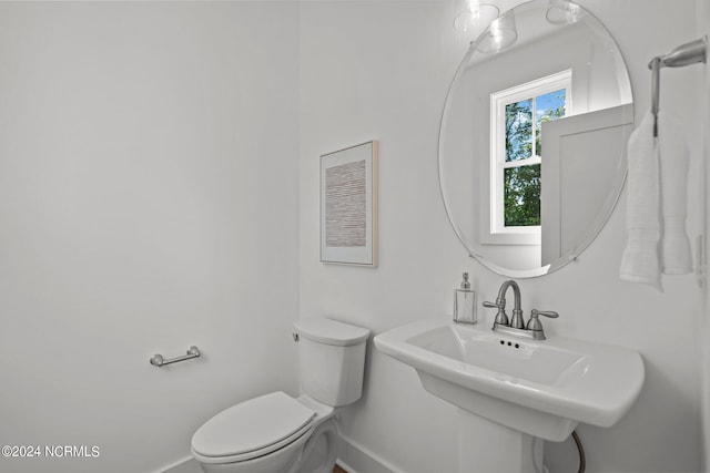 bathroom with toilet, baseboards, and a sink