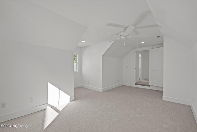 additional living space with visible vents, baseboards, a ceiling fan, light colored carpet, and vaulted ceiling