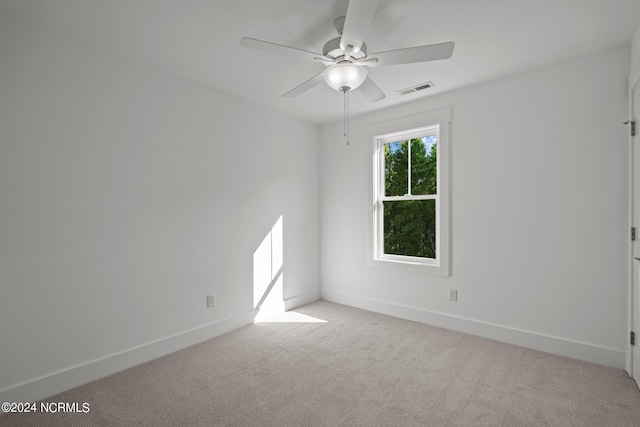 spare room featuring baseboards, a ceiling fan, visible vents, and light colored carpet