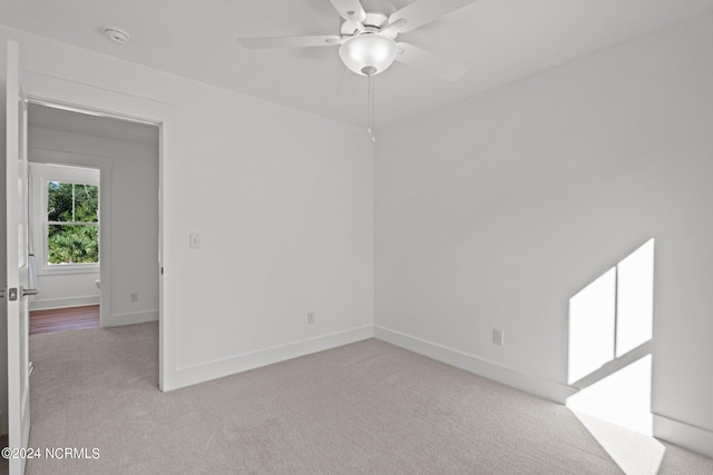 spare room featuring baseboards, a ceiling fan, and light colored carpet