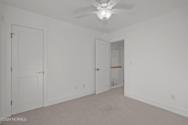 unfurnished bedroom featuring baseboards, a ceiling fan, and light colored carpet