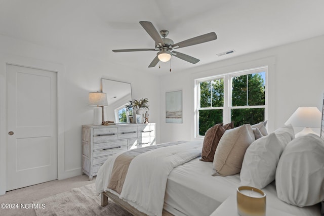 bedroom with a ceiling fan, visible vents, light carpet, and multiple windows