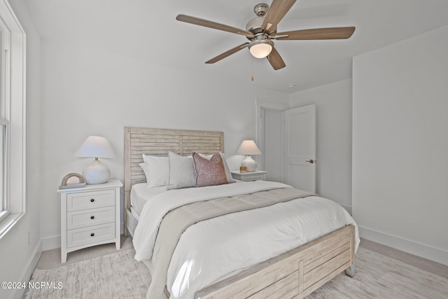 bedroom featuring a ceiling fan, light carpet, and baseboards