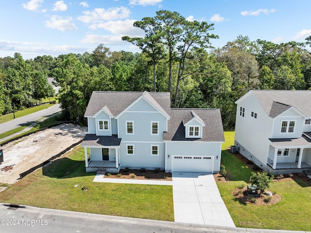 view of front of home featuring driveway, a front lawn, roof with shingles, and an attached garage