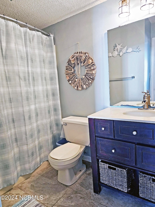 bathroom with a textured ceiling, tile flooring, toilet, and vanity