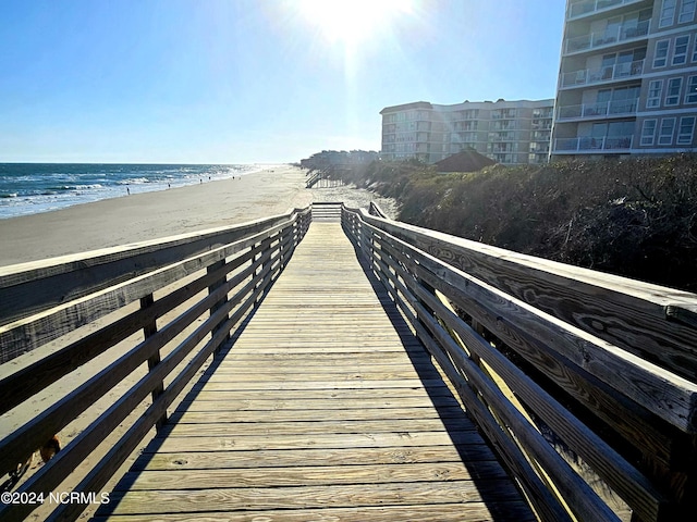 view of dock with a beach view and a water view