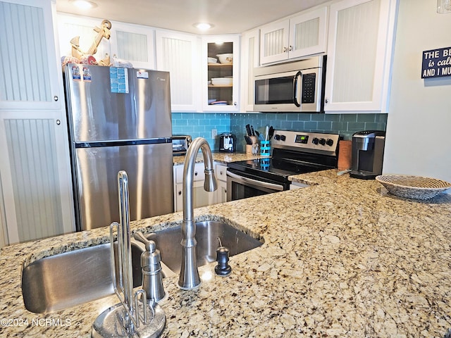 kitchen featuring white cabinets, tasteful backsplash, stainless steel appliances, and light stone counters