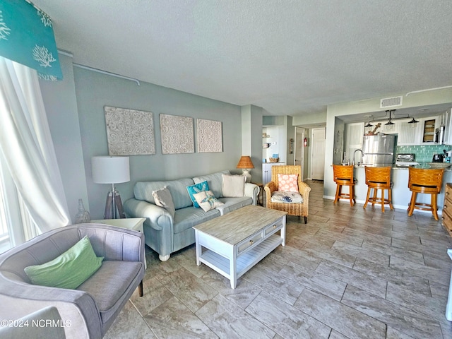 tiled living room featuring sink and a textured ceiling