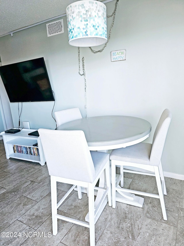 dining area with a textured ceiling and light tile flooring