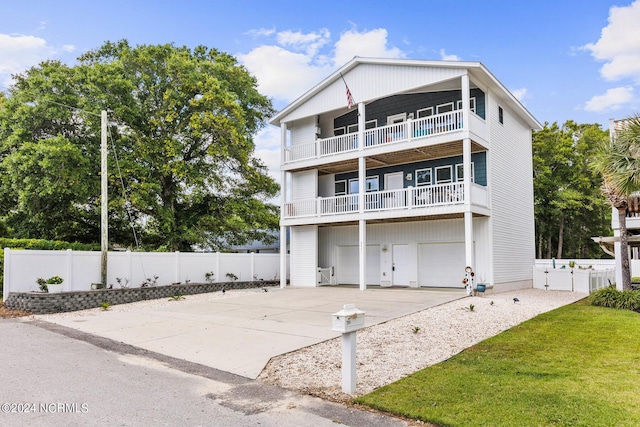 rear view of house with a balcony, a gate, fence, a garage, and concrete driveway