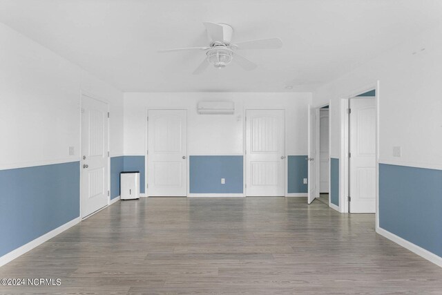 empty room with a wall unit AC, ceiling fan, and dark hardwood / wood-style flooring