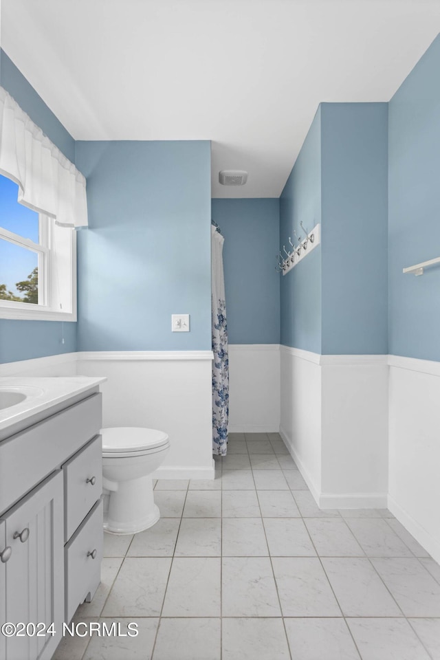 bathroom featuring toilet, vanity, visible vents, and wainscoting